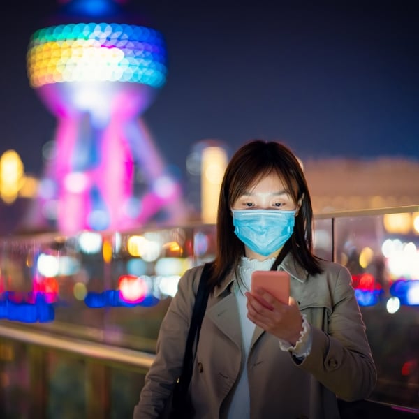 woman travel face mask on cell phone