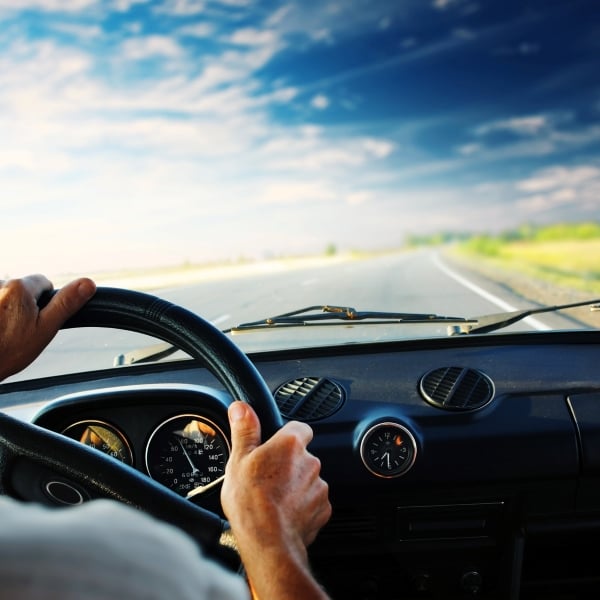 photo man's hands on steering wheel and open road