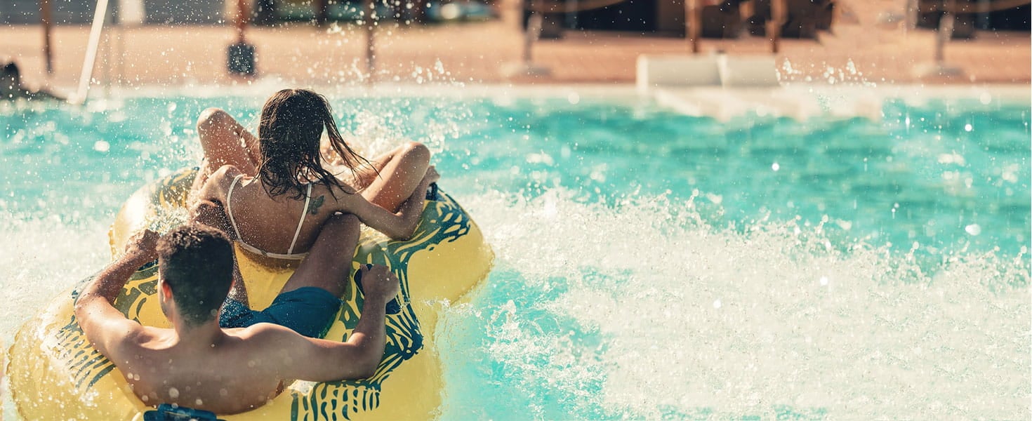 two people on a rafting tube splashing into a pool