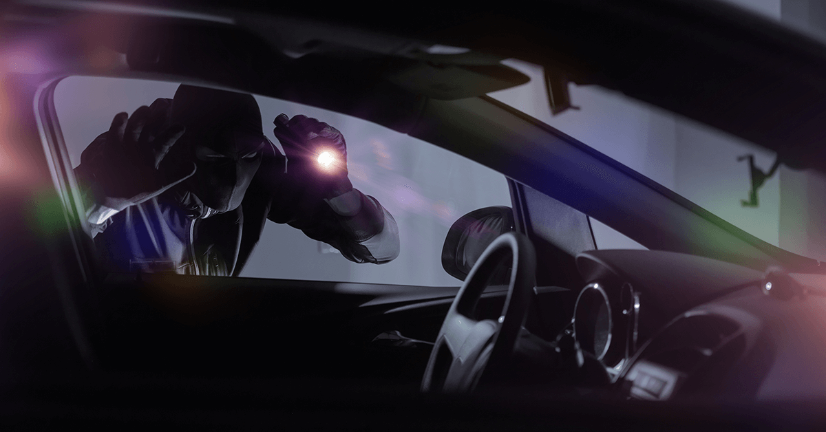 A car thief looking into a car window